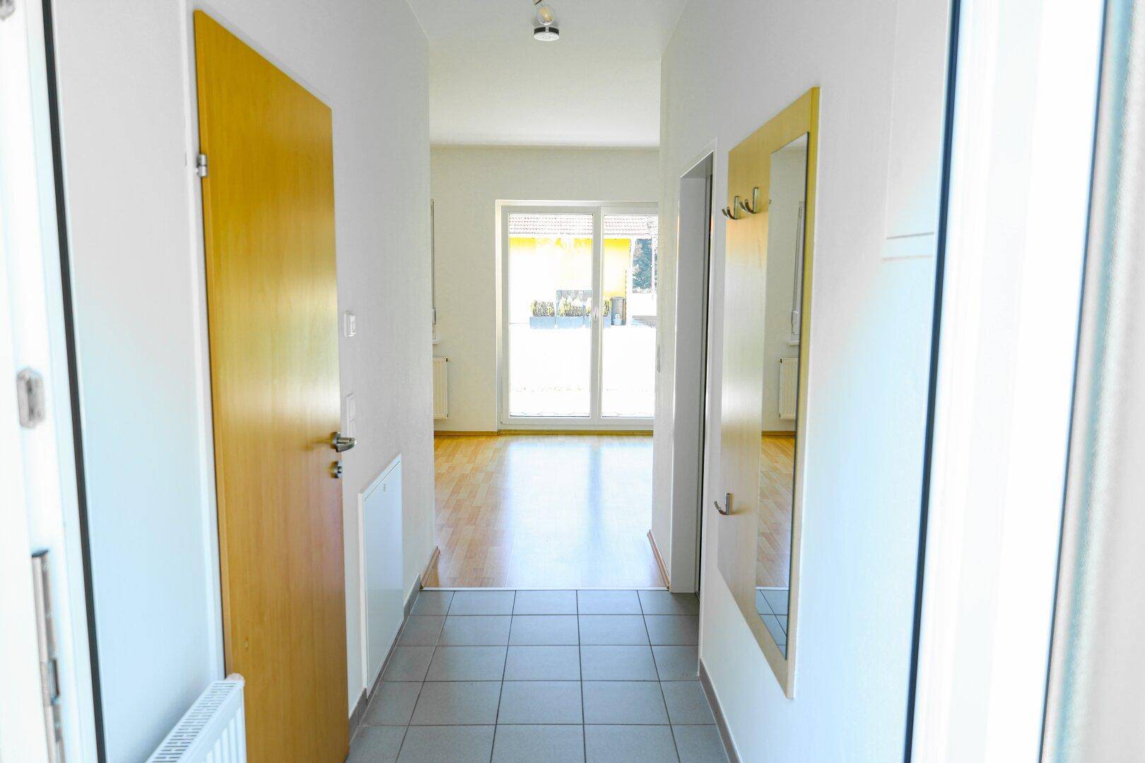 Heller Flur mit Fliesenboden, Garderobe und Blick zum Wohnbereich.