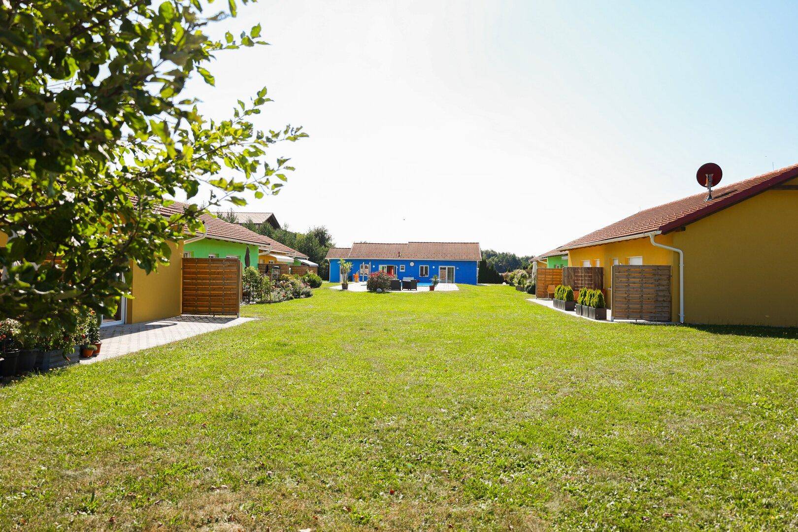 Weitläufiger Rasenbereich umgeben von bunten Häusern unter klarem Himmel.