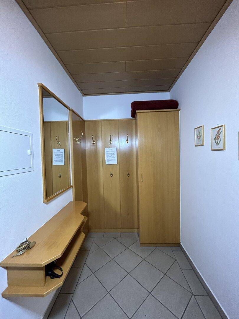 Eingangsbereich mit Garderobe, Spiegel und praktischen Holzschränken für zusätzlichen Stauraum.