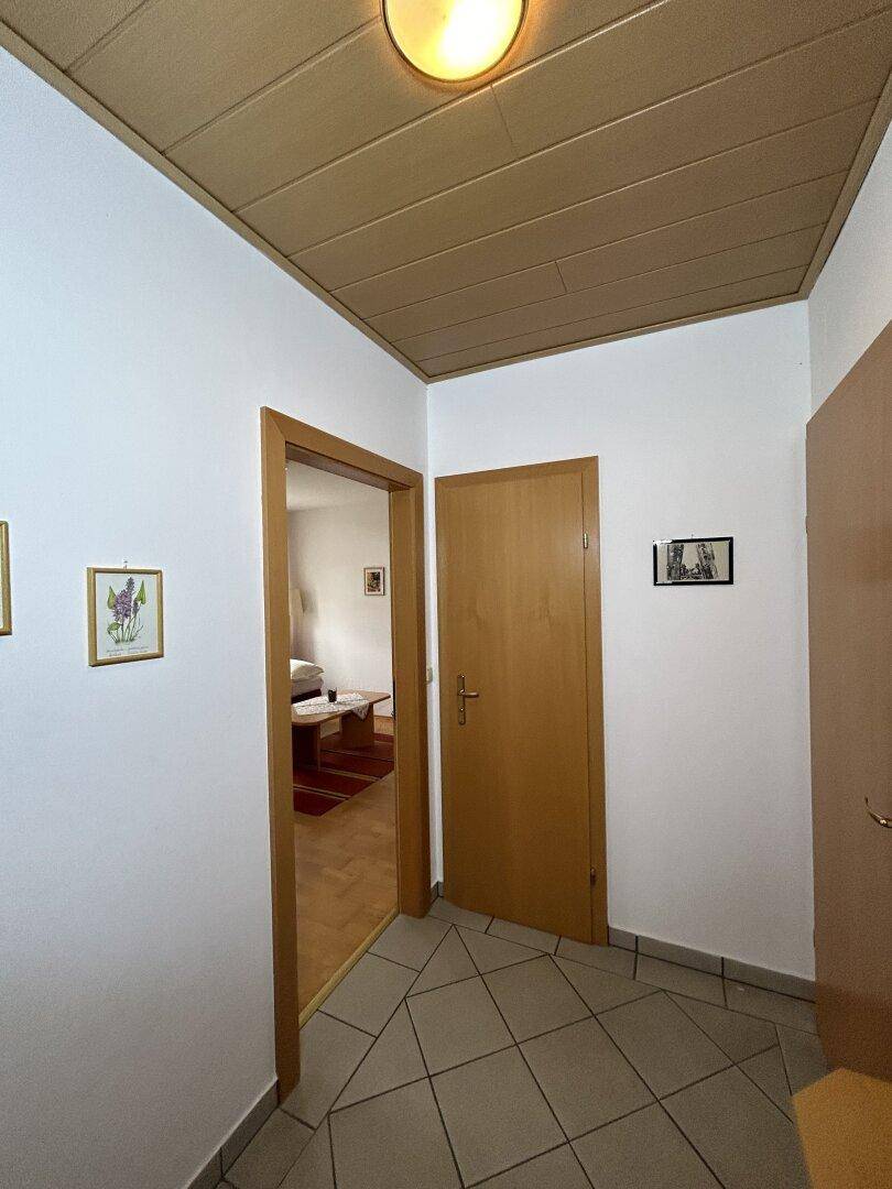 Flur mit Fliesenboden und Holztüren, bietet Zugang zu verschiedenen Räumen der Wohnung.