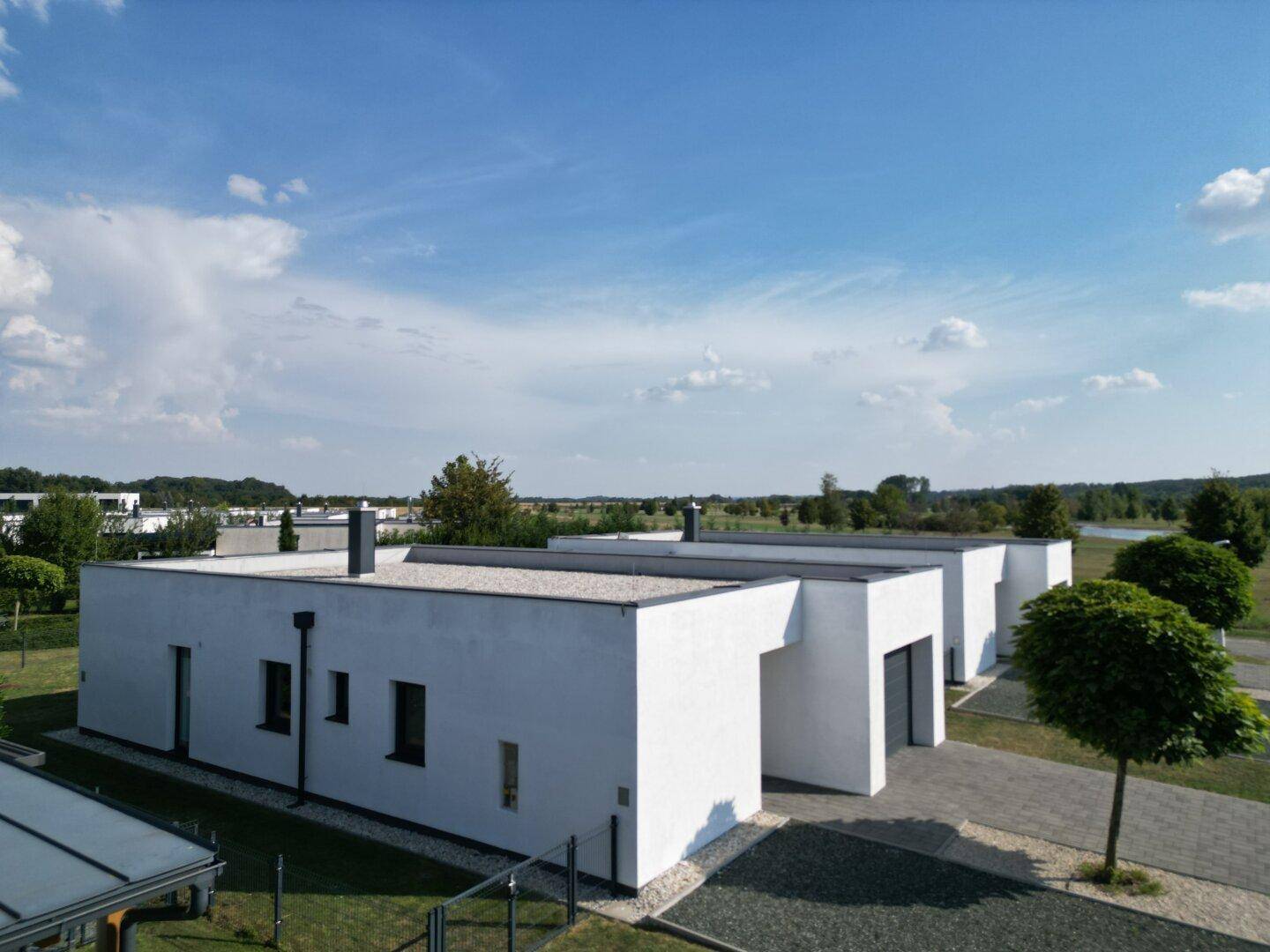 Eine Reihe von modernen, weiß verputzten Häusern mit Flachdächern und minimalistischer Architektur in ländlicher Umgebung.