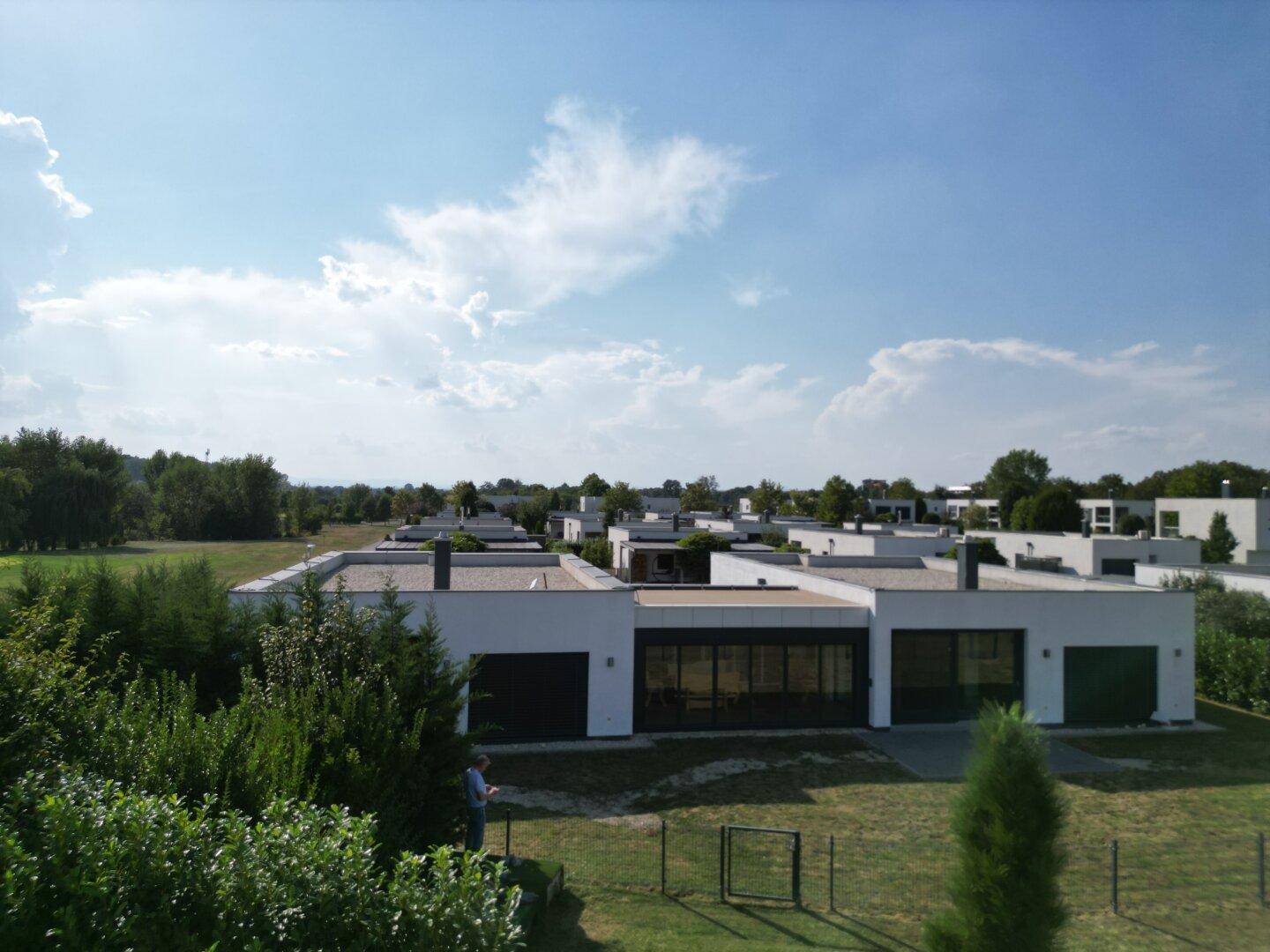 Weitläufige Ansicht einer modernen Wohnsiedlung mit minimalistischen Häusern und viel Grün in der Umgebung.