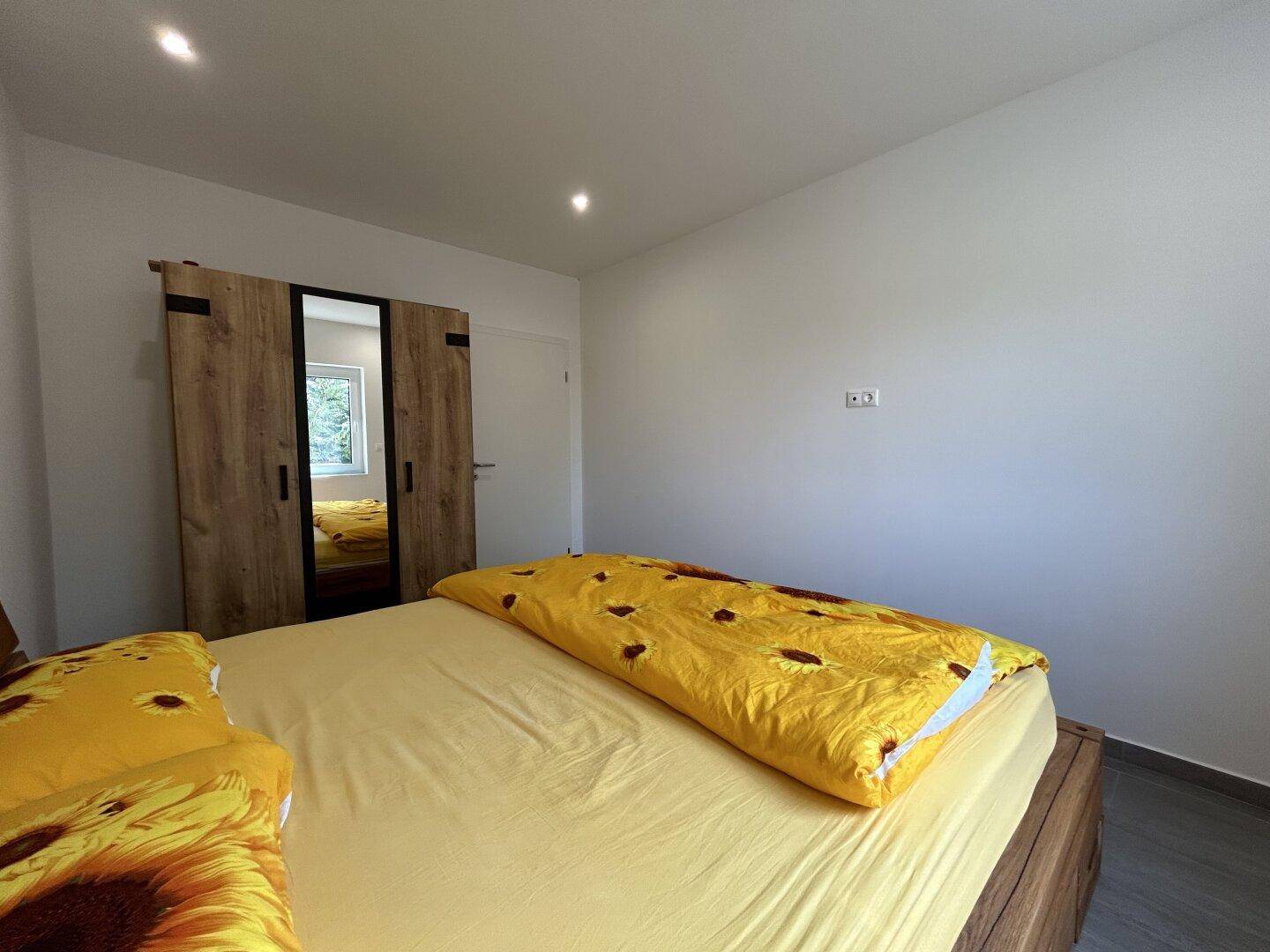 Schlafzimmer mit praktischem Kleiderschrank und gemütlichem Holzbett.