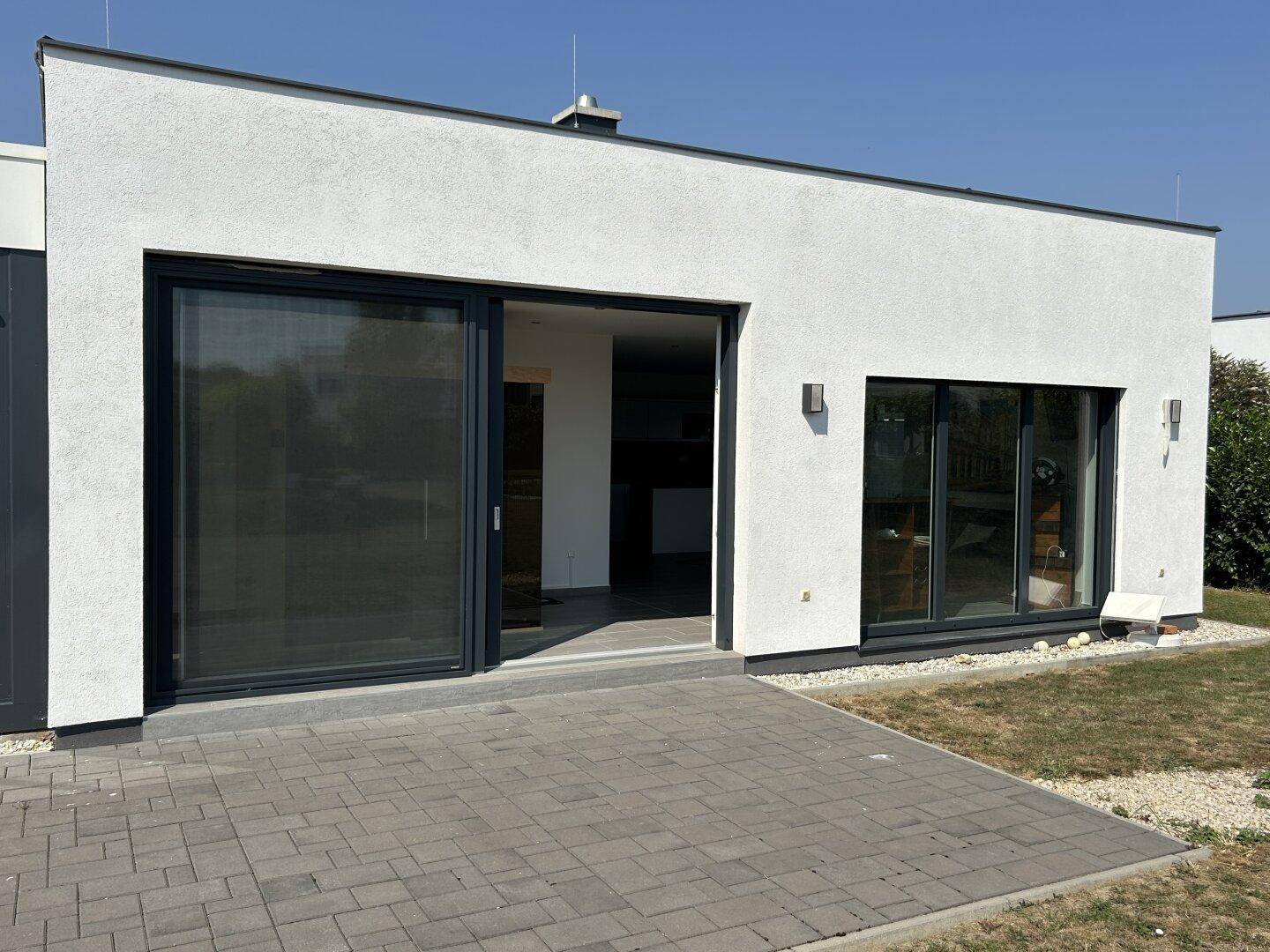 Zeitgenössisches Haus mit großzügiger Terrasse und breiter Schiebetür zum Garten.