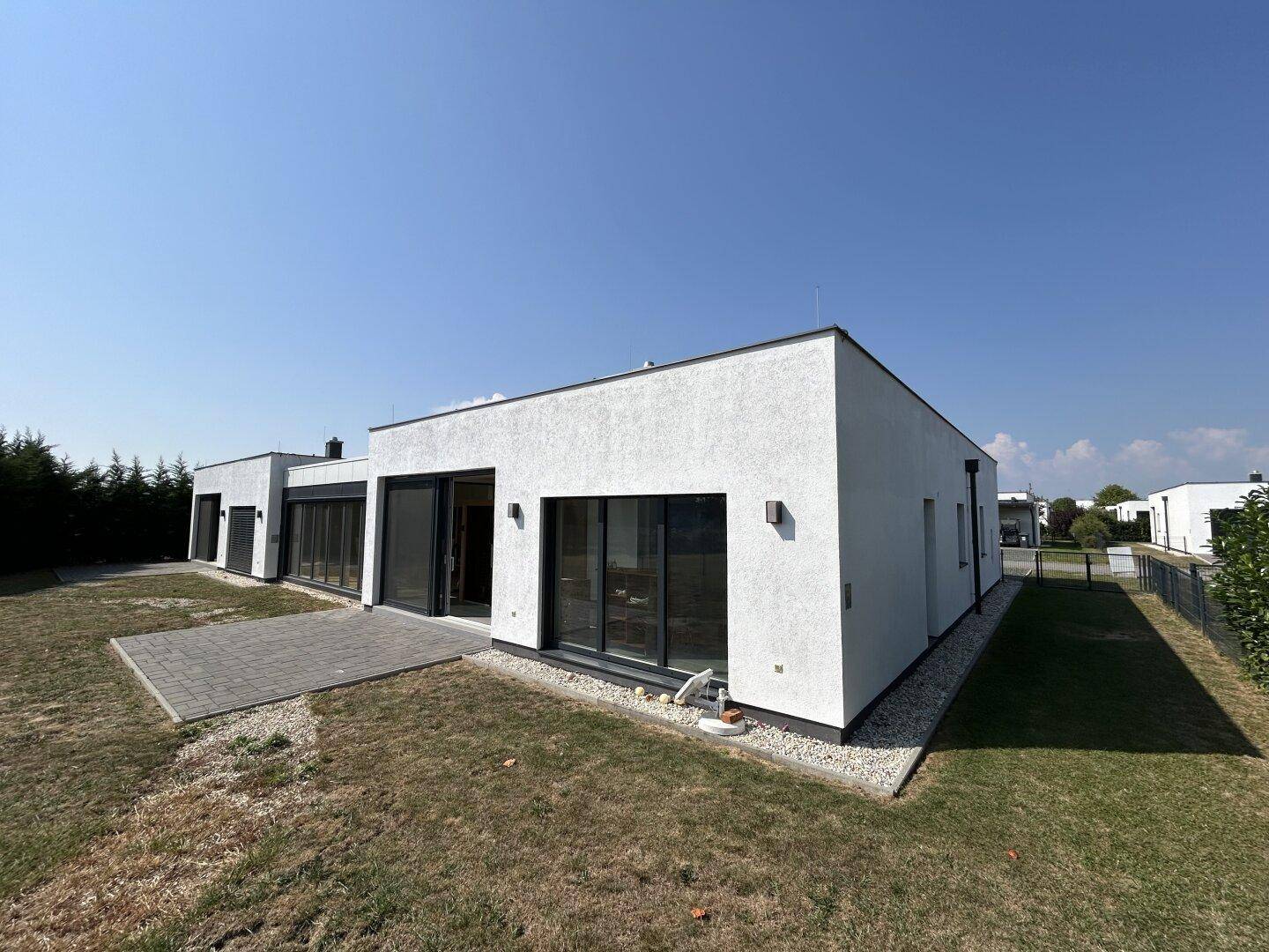 Weitläufige Ansicht des modernen Hauses mit Flachdach, Terrasse und weitläufigem Grundstück.