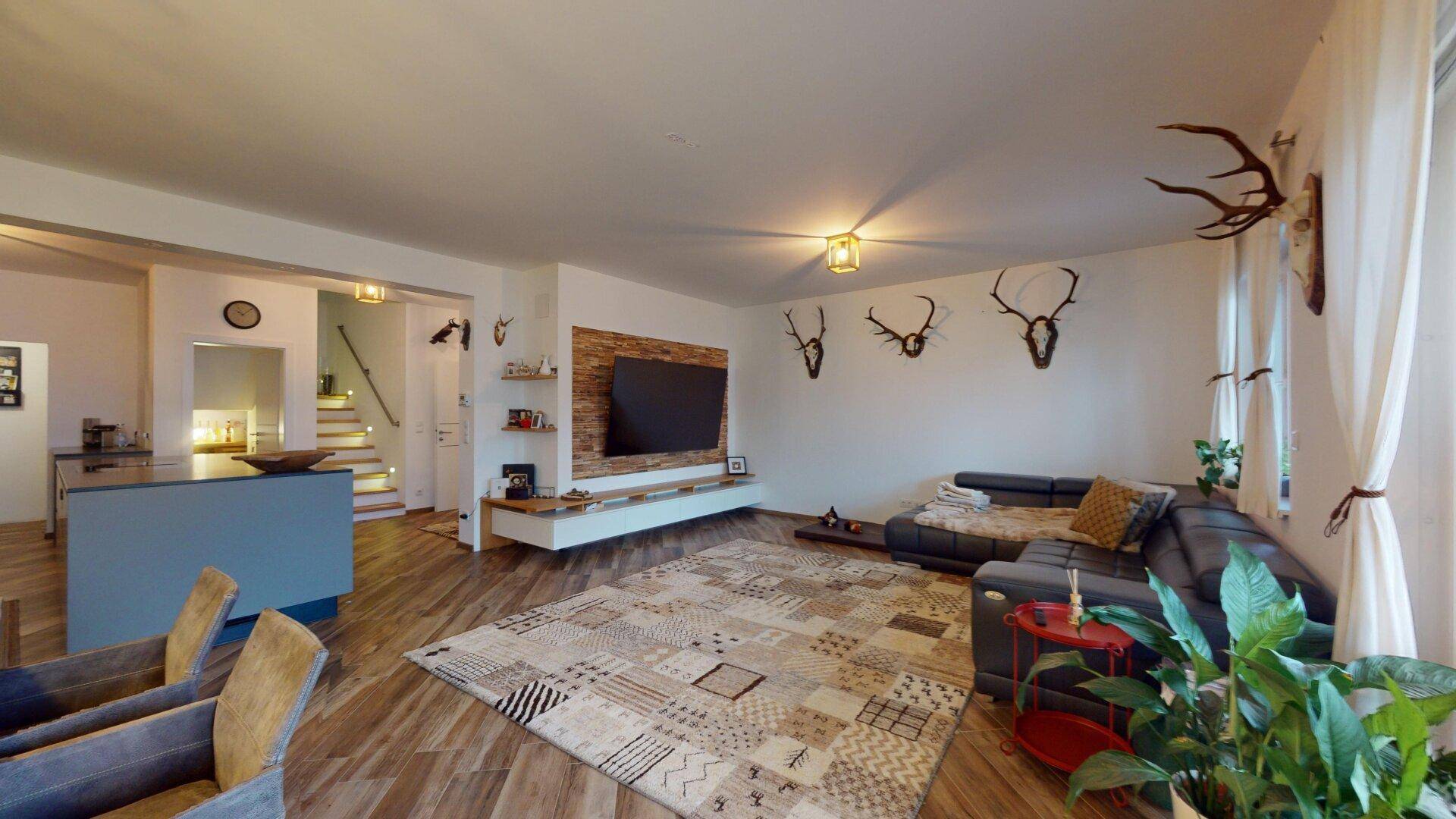 Helles Wohnzimmer mit großem Sofa, TV-Wand und rustikalen Hirschgeweih-Dekorationen.