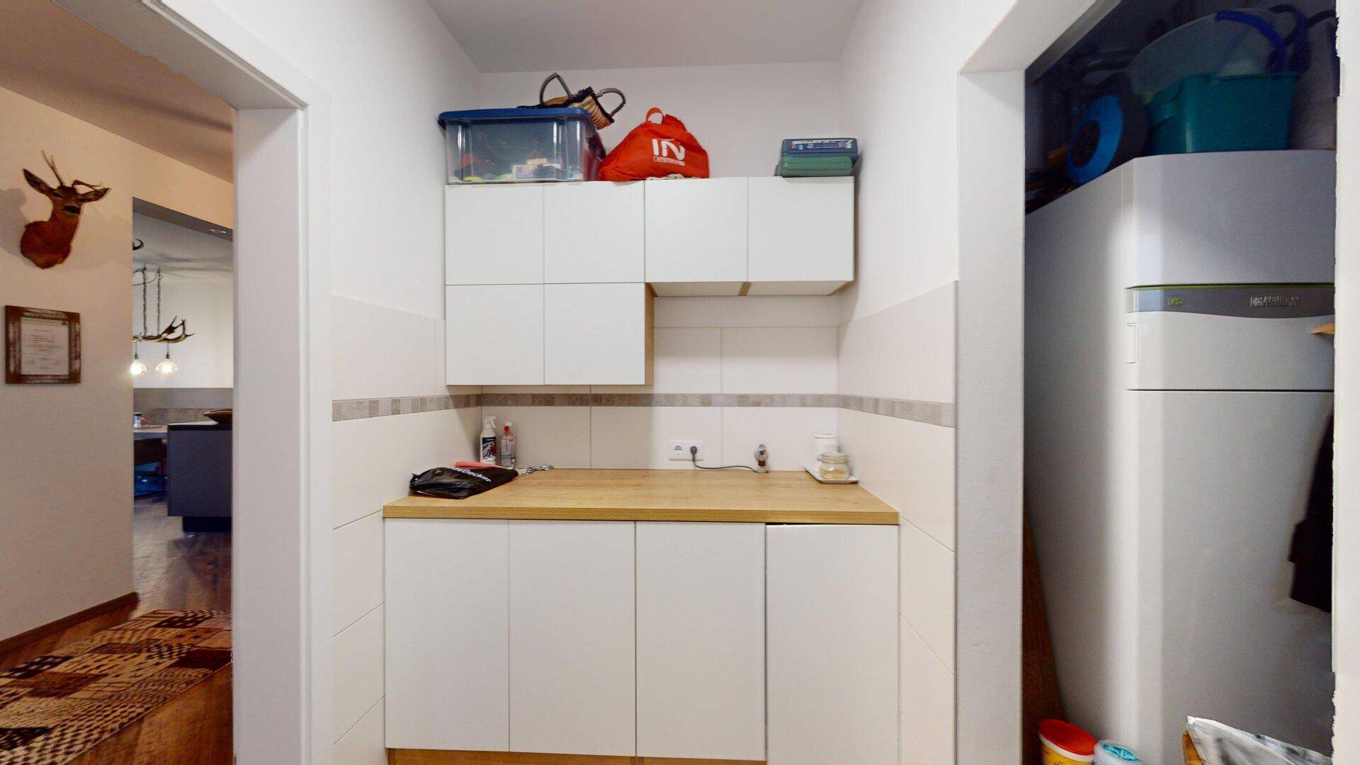 Kleiner Hauswirtschaftsraum mit Waschmaschine, Spülbecken und praktischen Hängeschränken.