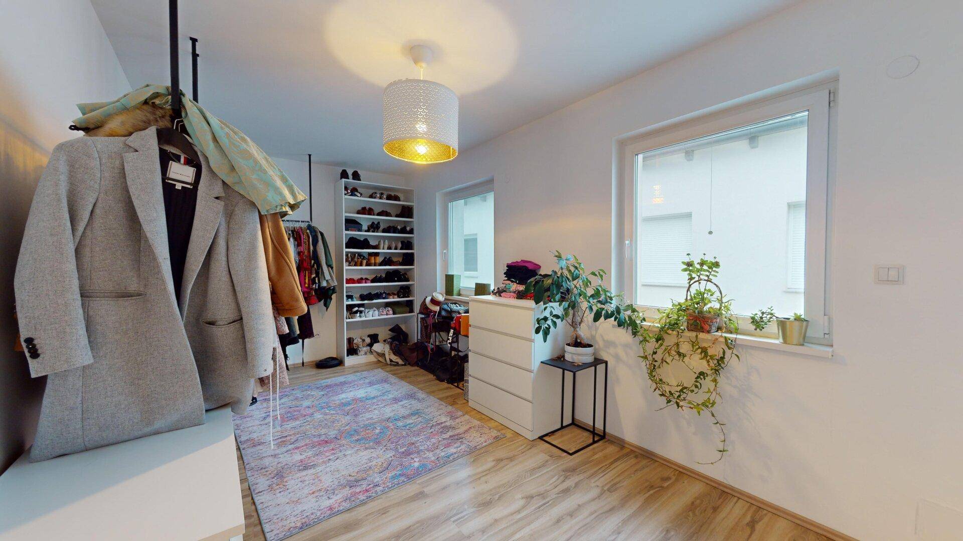 Geräumiger begehbarer Kleiderschrank mit viel Stauraum und natürlichem Lichteinfall durch ein Fenster.