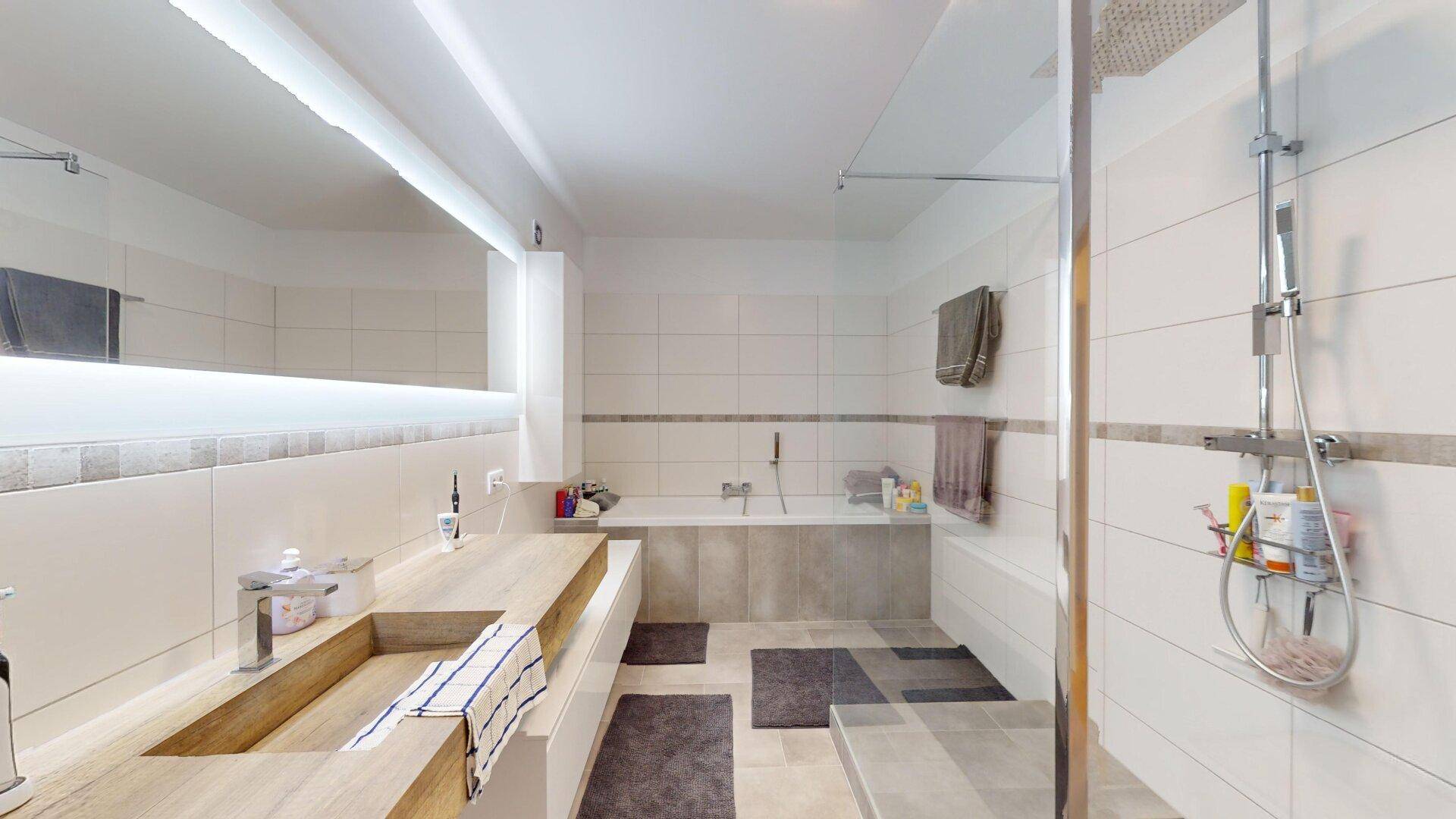 Geräumiges Badezimmer mit Badewanne, begehbarer Dusche und modernem Doppelwaschbecken.