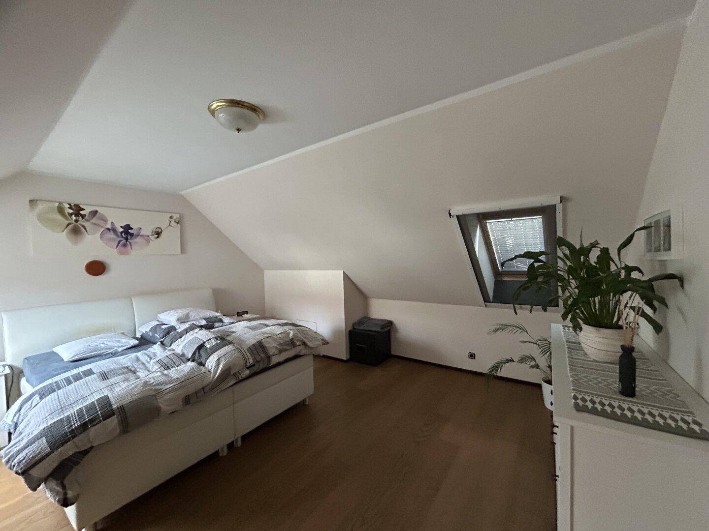 Geräumiges Schlafzimmer im Dachgeschoss mit Doppelbett, Holzboden und Dachfenster.