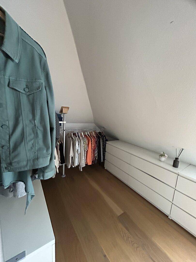 Begehbarer Kleiderschrank im Dachgeschoss mit viel Stauraum und Holzboden.