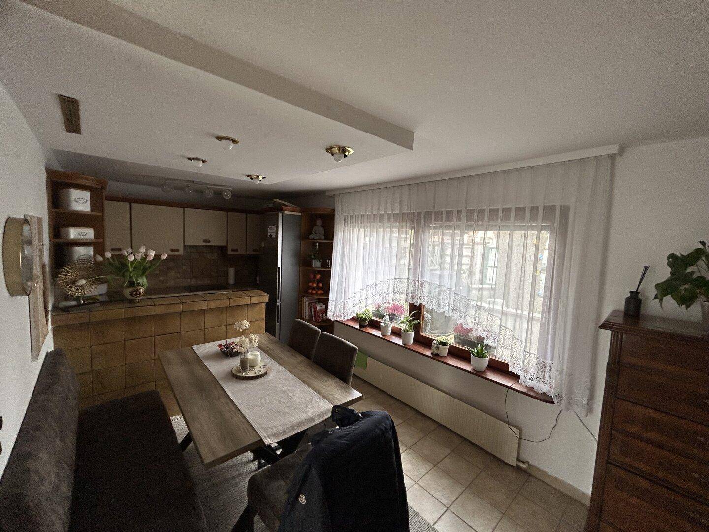 Gemütliche Wohnküche mit Essbereich, Fliesenboden und großem Fenster.