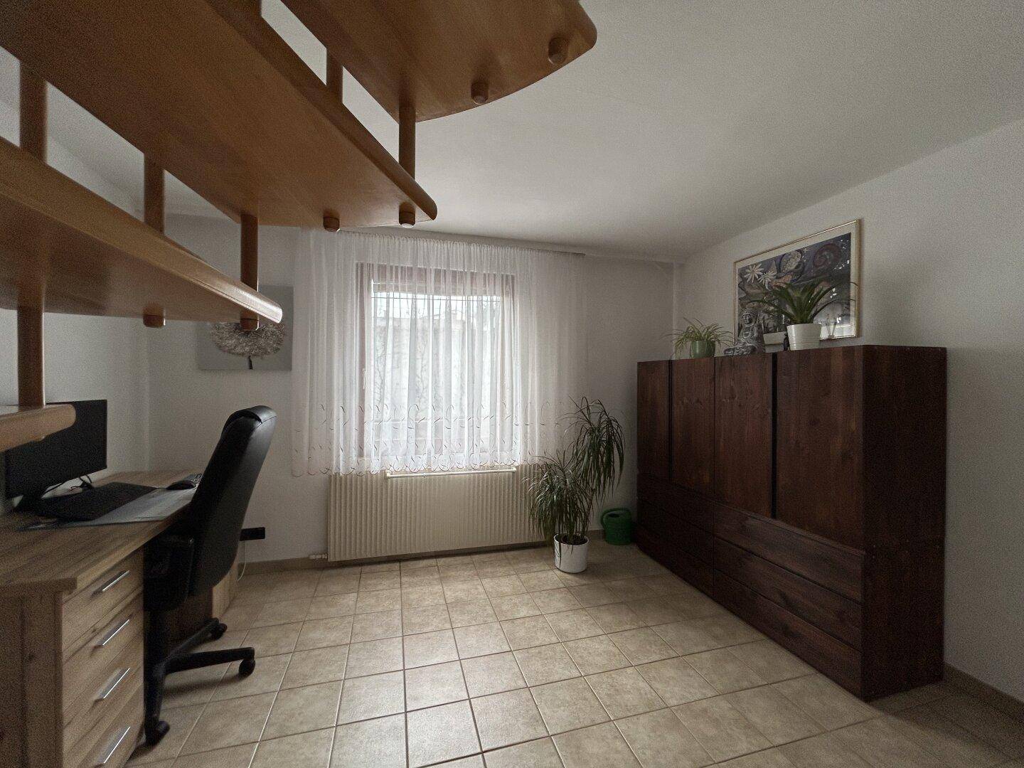 Arbeitsbereich mit Fliesenboden, Schreibtisch und Fenster, unter der Wendeltreppe gelegen.