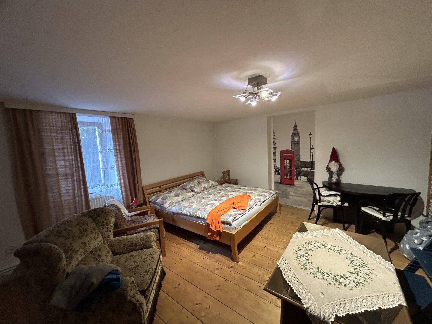 Schlafzimmer mit Holzdielenboden, Doppelbett und Wandbild mit London-Motiv.