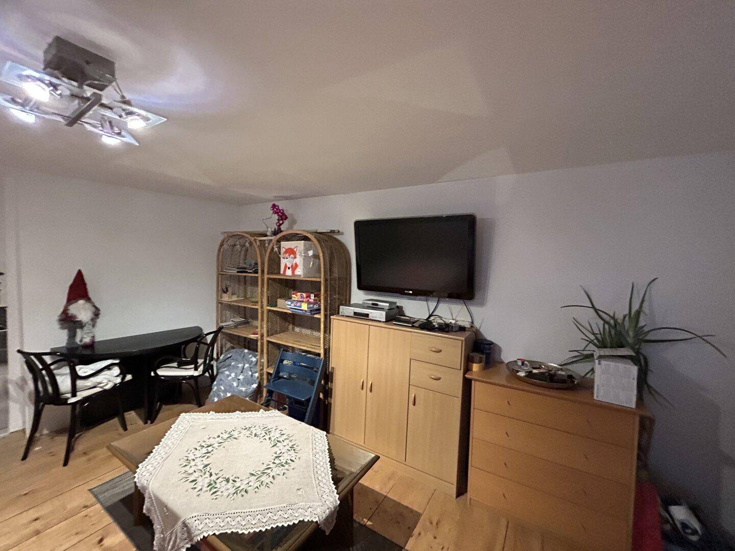 Wohnbereich mit Holzdielenboden, Fernseher und rustikalen Möbeln.
