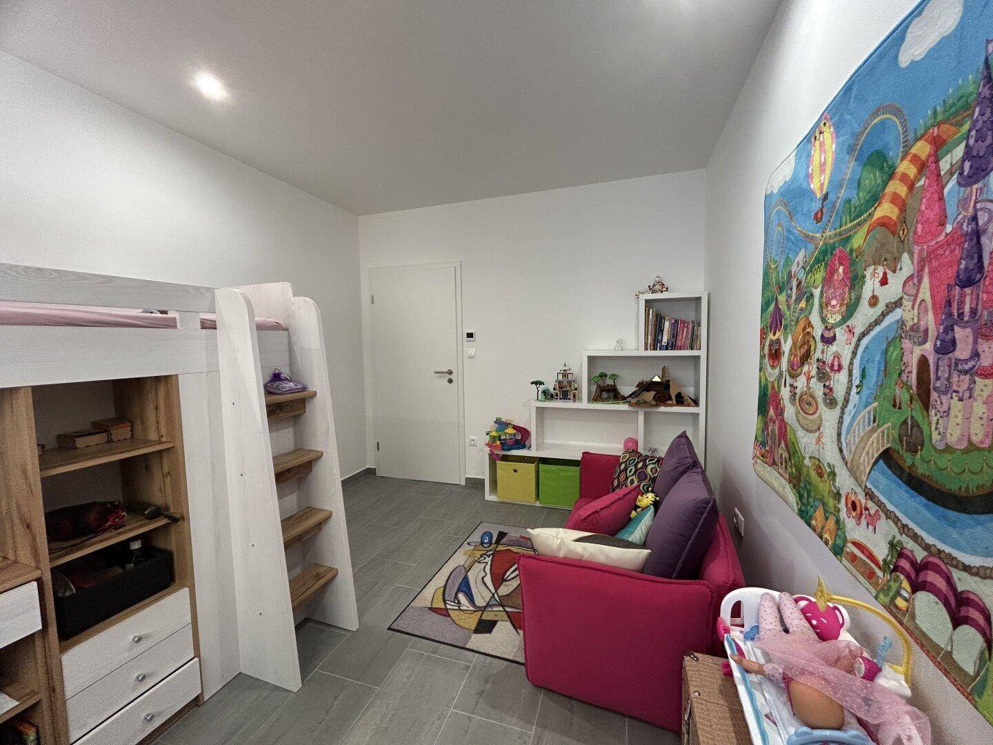 Helles Kinderzimmer mit Hochbett, Spielteppich und bunten Dekorationen an der Wand.