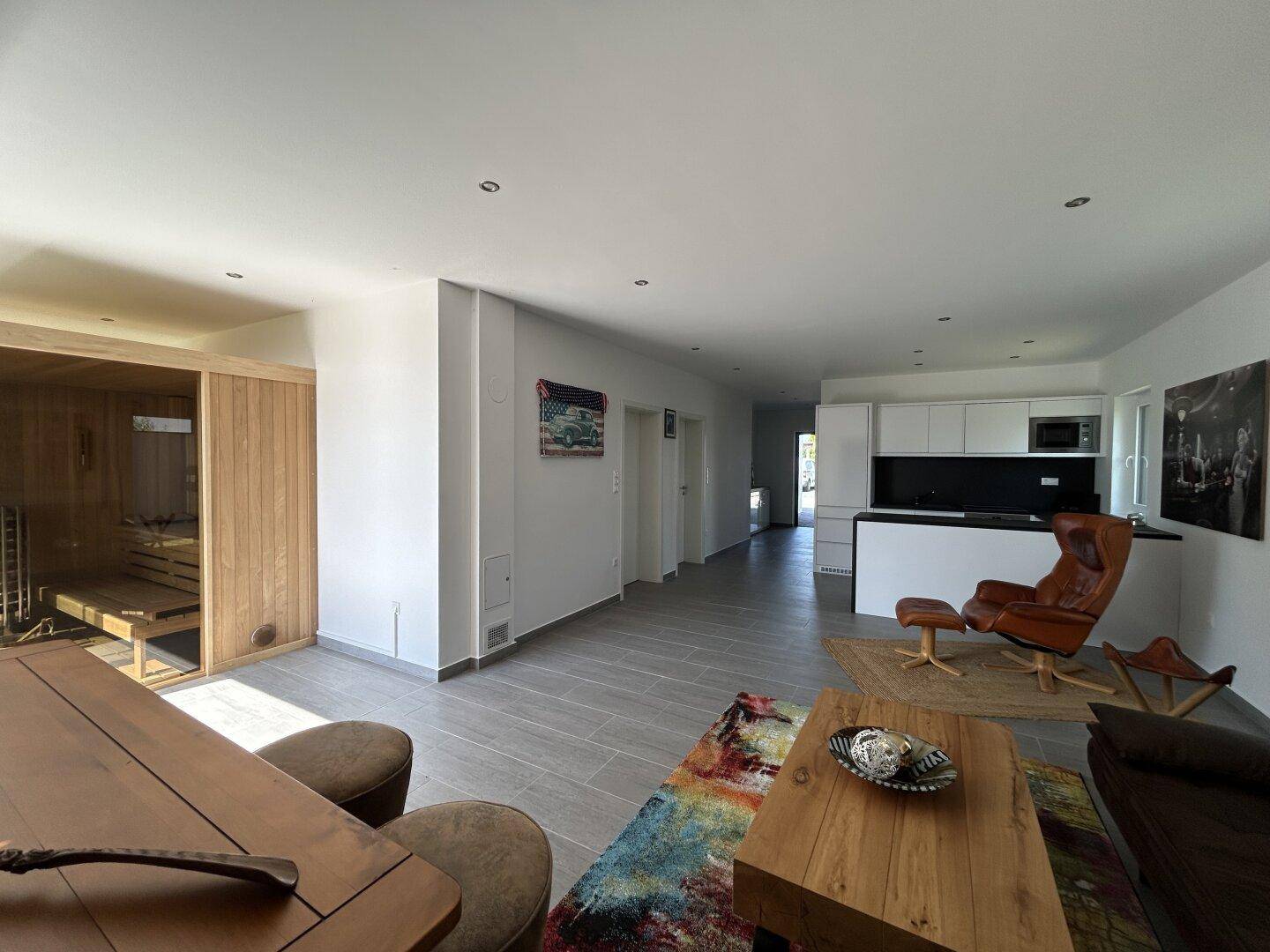 Geräumiger offener Wohnbereich mit Essbereich, integrierter Küche und sichtbarer Sauna im Hintergrund.
