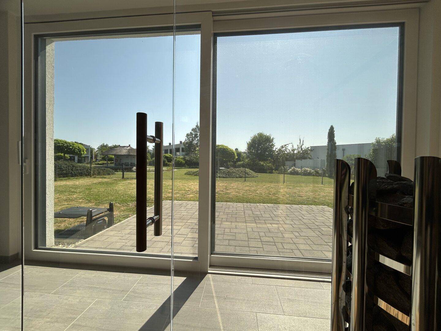 Weitläufiger Blick aus dem Innenraum durch große Fenster auf den gepflegten Gartenbereich.
