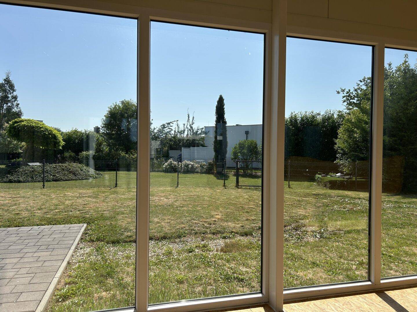 Panoramaaussicht aus dem Wintergarten auf den gepflegten Garten und die umliegende Landschaft.