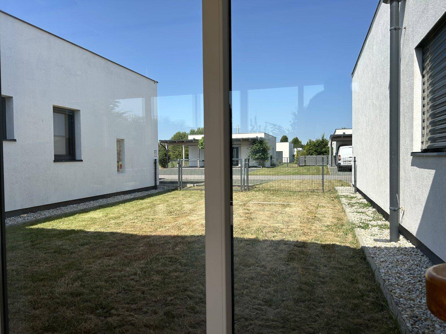Blick aus dem Wintergarten auf den kleinen Innenhof und die benachbarten modernen Häuser.