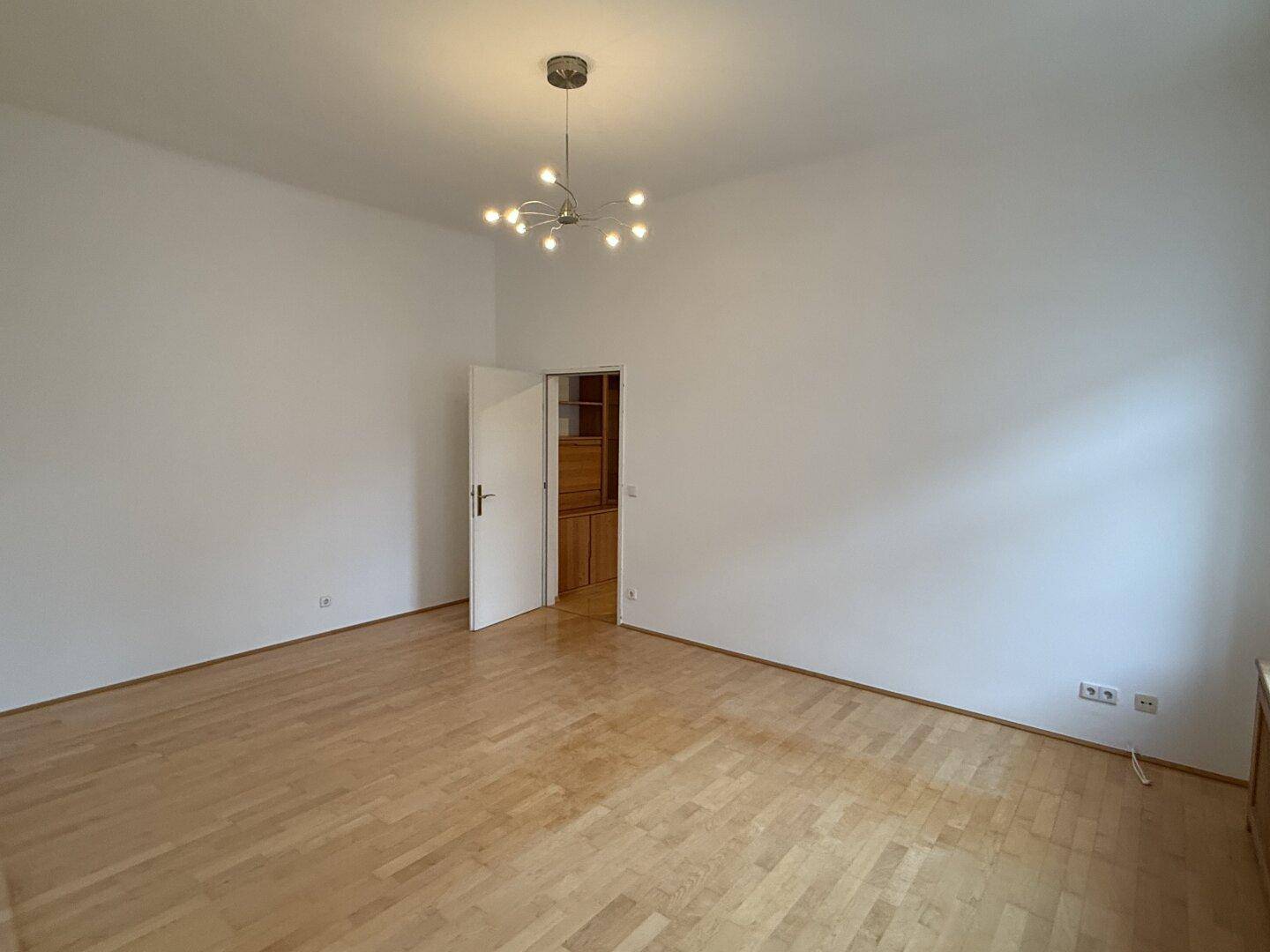 Leerer Raum mit Parkettboden und einer modernen Deckenleuchte.