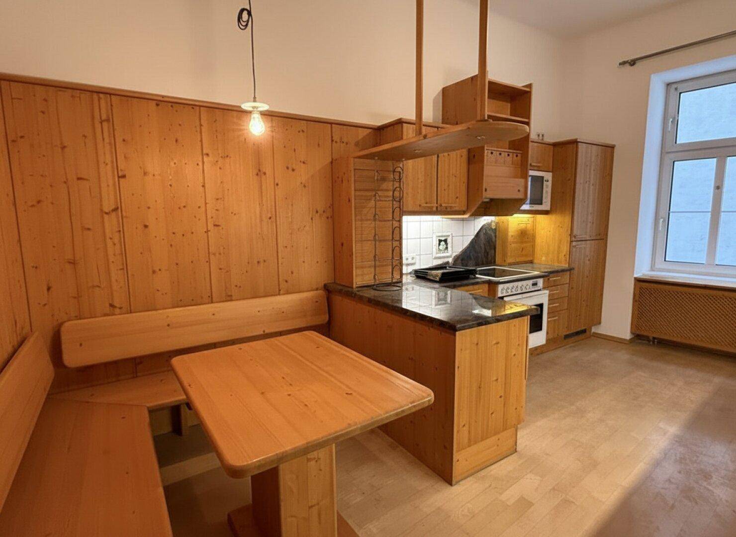 Traditionelle Holzküche mit Essecke, Granitarbeitsplatten und integrierten Geräten.