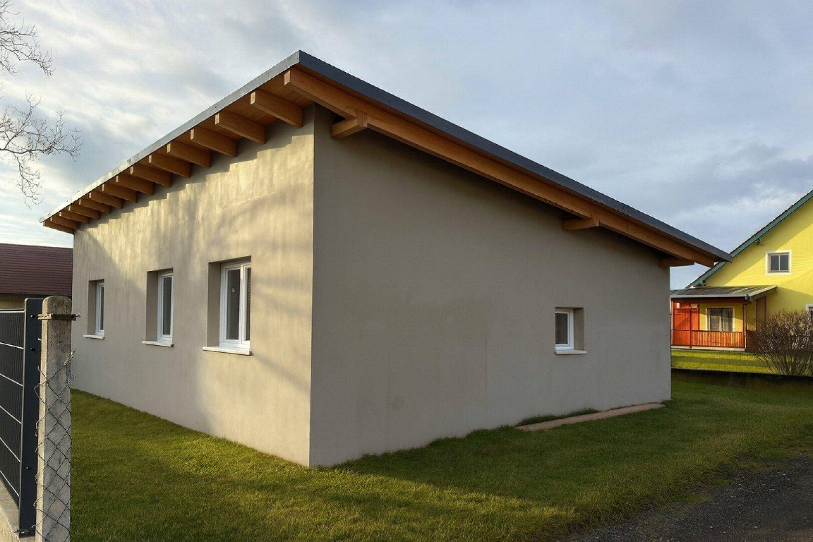 Rückseite des modernen Neubaus mit mehreren Fenstern und sichtbarer Dachkonstruktion.
