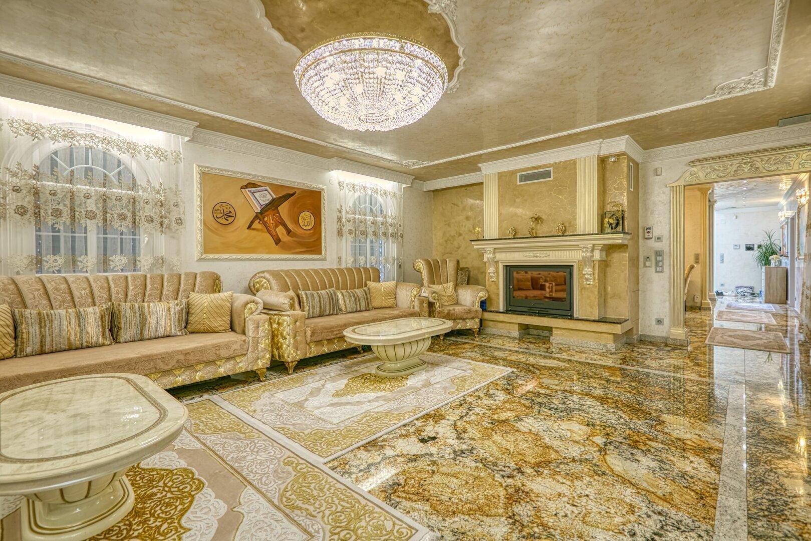 Geräumiges Wohnzimmer mit opulentem Dekor, Marmorboden und einem eleganten Kamin als Mittelpunkt.