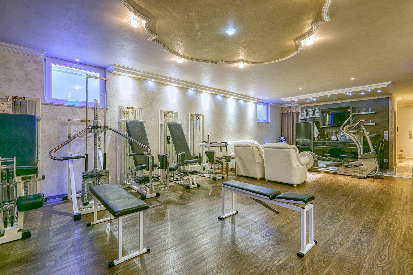 Gut ausgestatteter Fitnessraum mit Trainingsgeräten und einem Entspannungsbereich, modern eingerichtet.