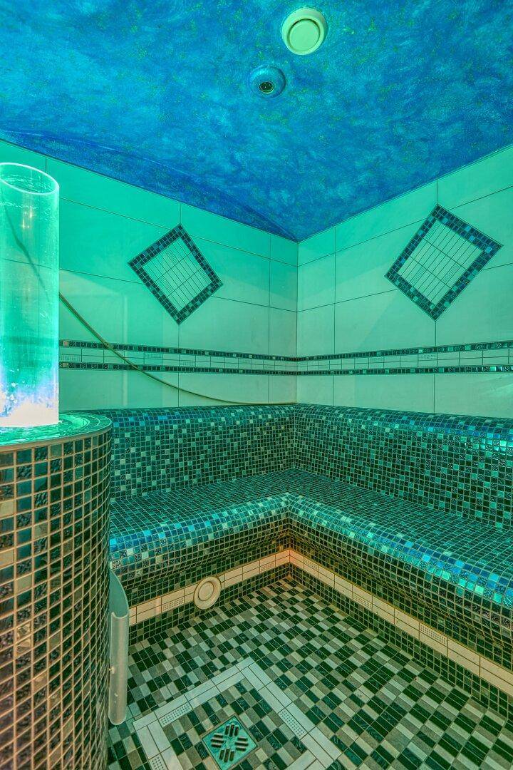 Dampfbad mit blauen Mosaikfliesen und stimmungsvoller Beleuchtung für Entspannung, sehr modern.