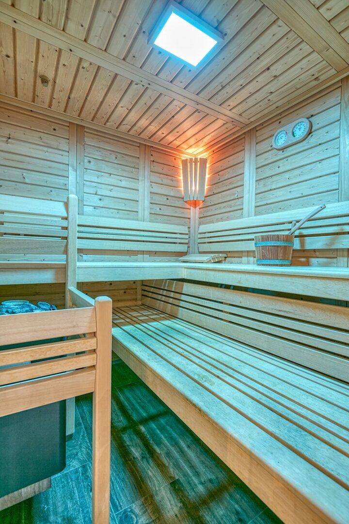 Innenansicht einer Holzsauna mit mehreren Bänken und stimmungsvoller Beleuchtung, sehr einladend.