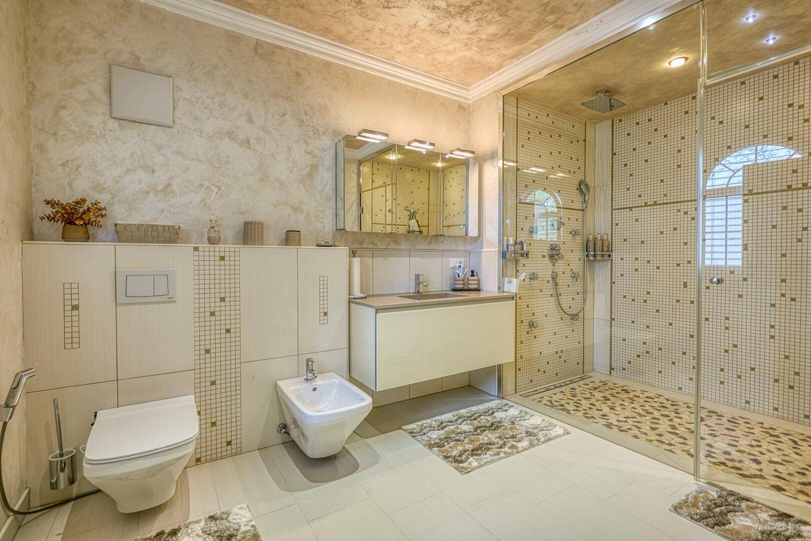 Modernes Badezimmer mit begehbarer Dusche, Bidet und stilvollen Fliesen, gut beleuchtet.