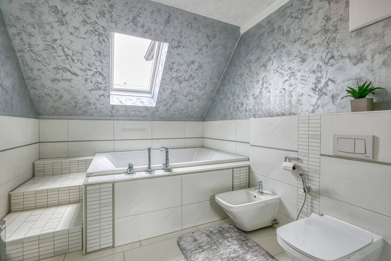Geräumiges Badezimmer im Dachgeschoss mit Badewanne, Bidet und Dachfenster, sehr hell.