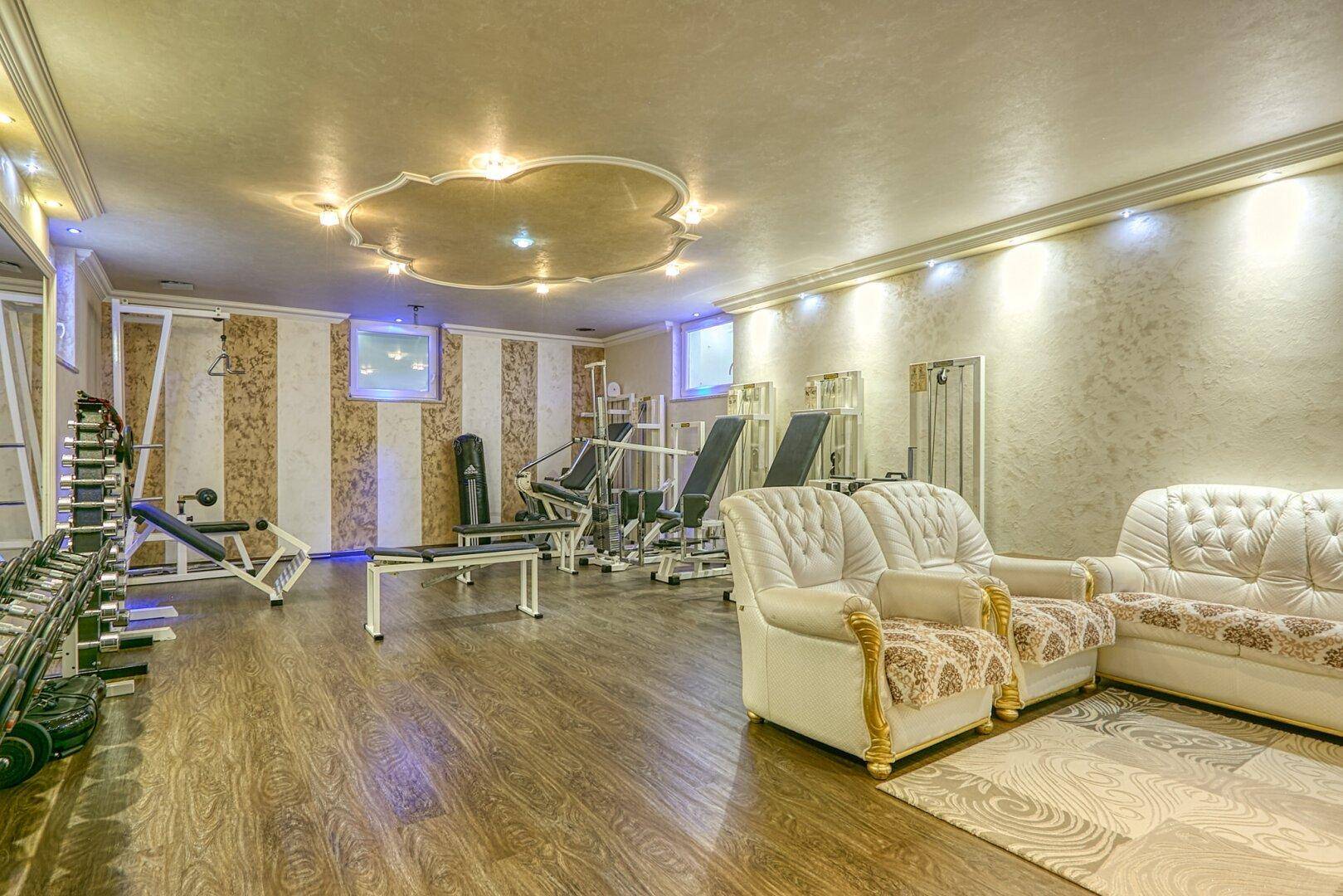 Geräumiger Fitnessraum mit verschiedenen Trainingsgeräten und Sitzgelegenheiten, gut ausgestattet.