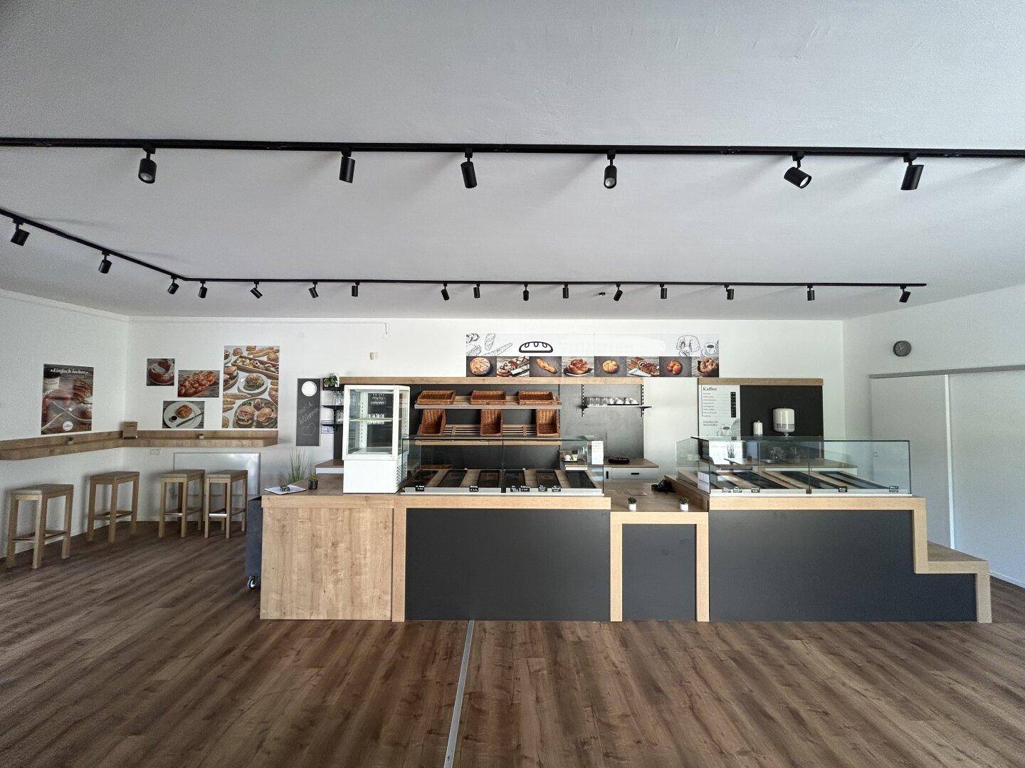 Moderner Verkaufsraum mit Bäckereitheken, Regalen und Holzboden.