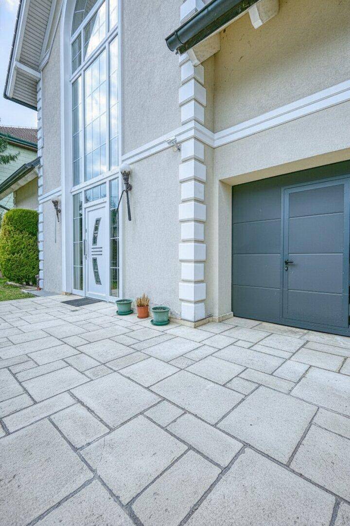 Hauseingang mit gepflastertem Vorplatz und integrierter Garage, sehr gepflegt und modern.