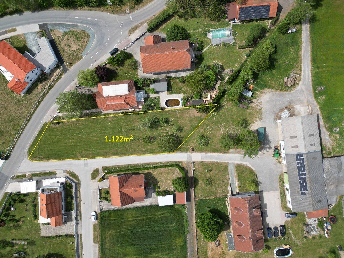 Luftaufnahme eines Grundstücks von 1.122 m² mit angrenzenden Häusern und Straßen.