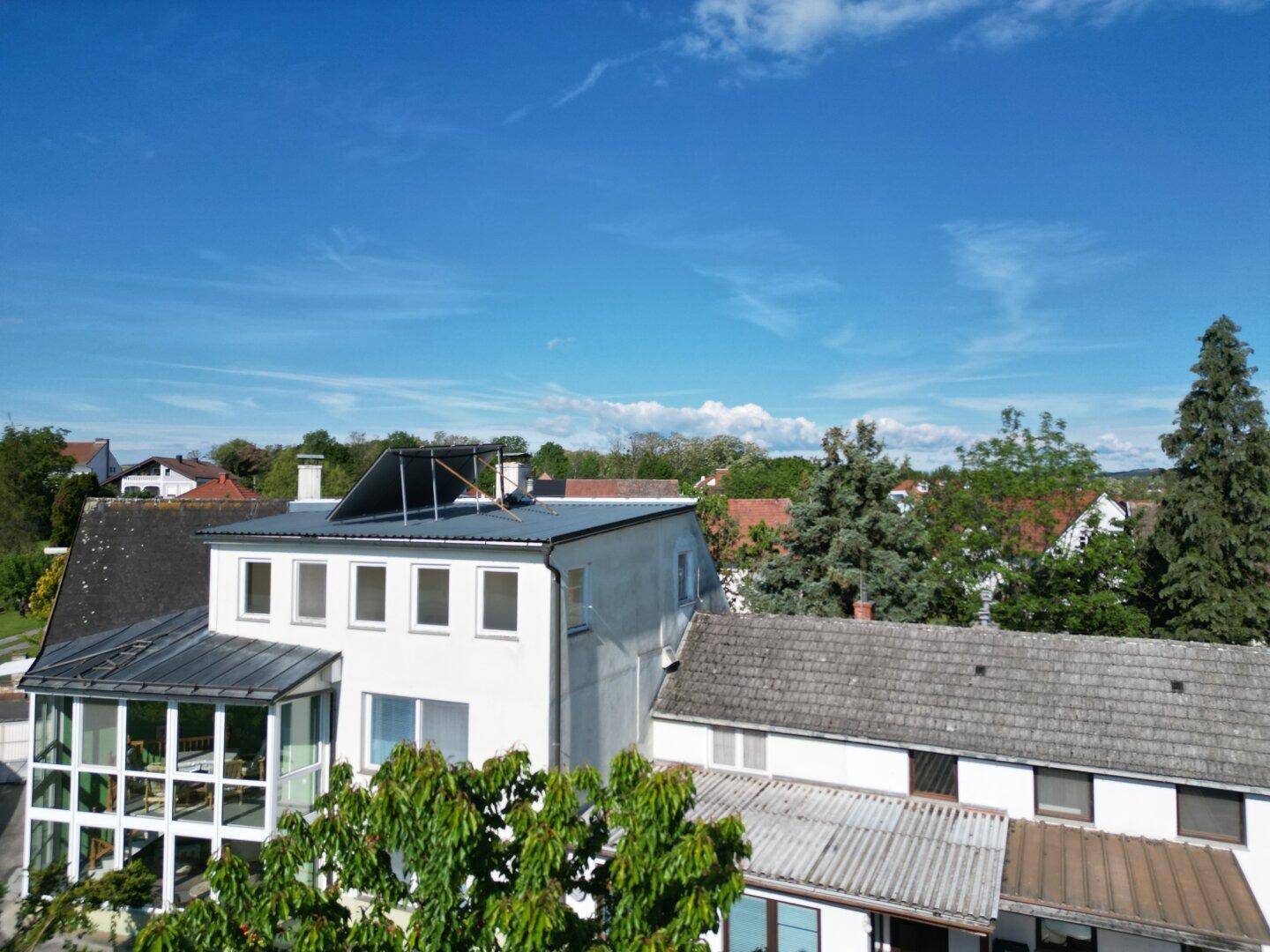 Gesamtansicht des Hauses mit Flachdach, Solaranlage und umliegender grüner Landschaft.
