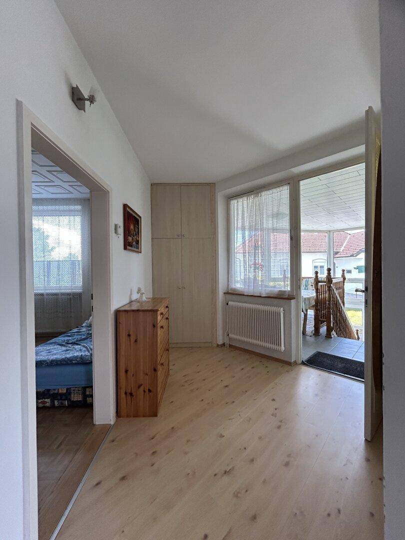 Heller Flur mit Holzfußboden, Einbauschränken und Zugang zum Wintergarten.