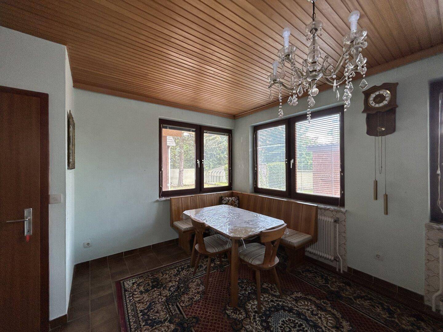 Gemütlicher Essbereich mit Eckbank, Holztäfelung an der Decke und traditionellem Kronleuchter.