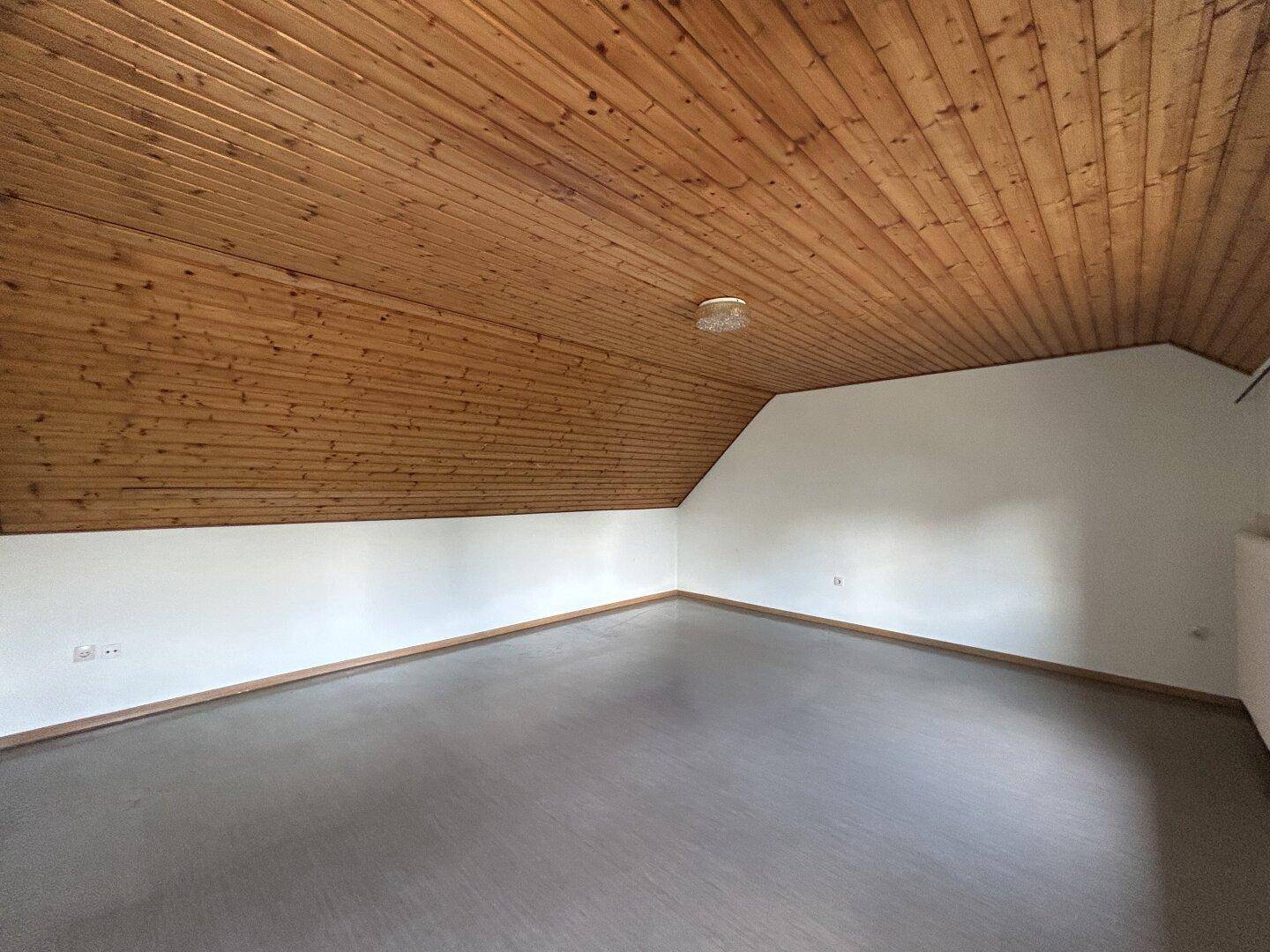 Heller Dachbodenraum mit sichtbarer Holztäfelung und schrägen Decken.