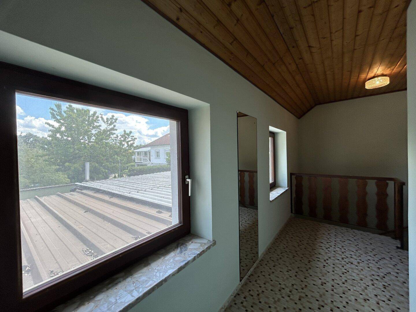 Heller Flur mit Fenster und Blick auf die Umgebung, ausgestattet mit Holzgeländer.