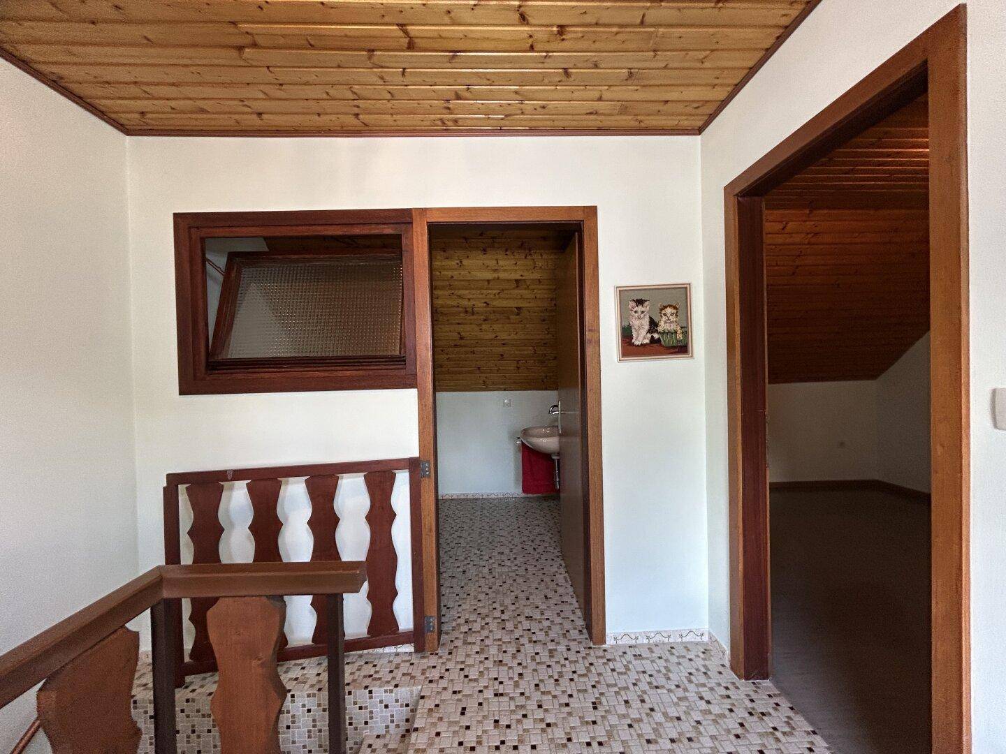 Flur mit Holztäfelung an der Decke und Zugang zu weiteren Räumen.