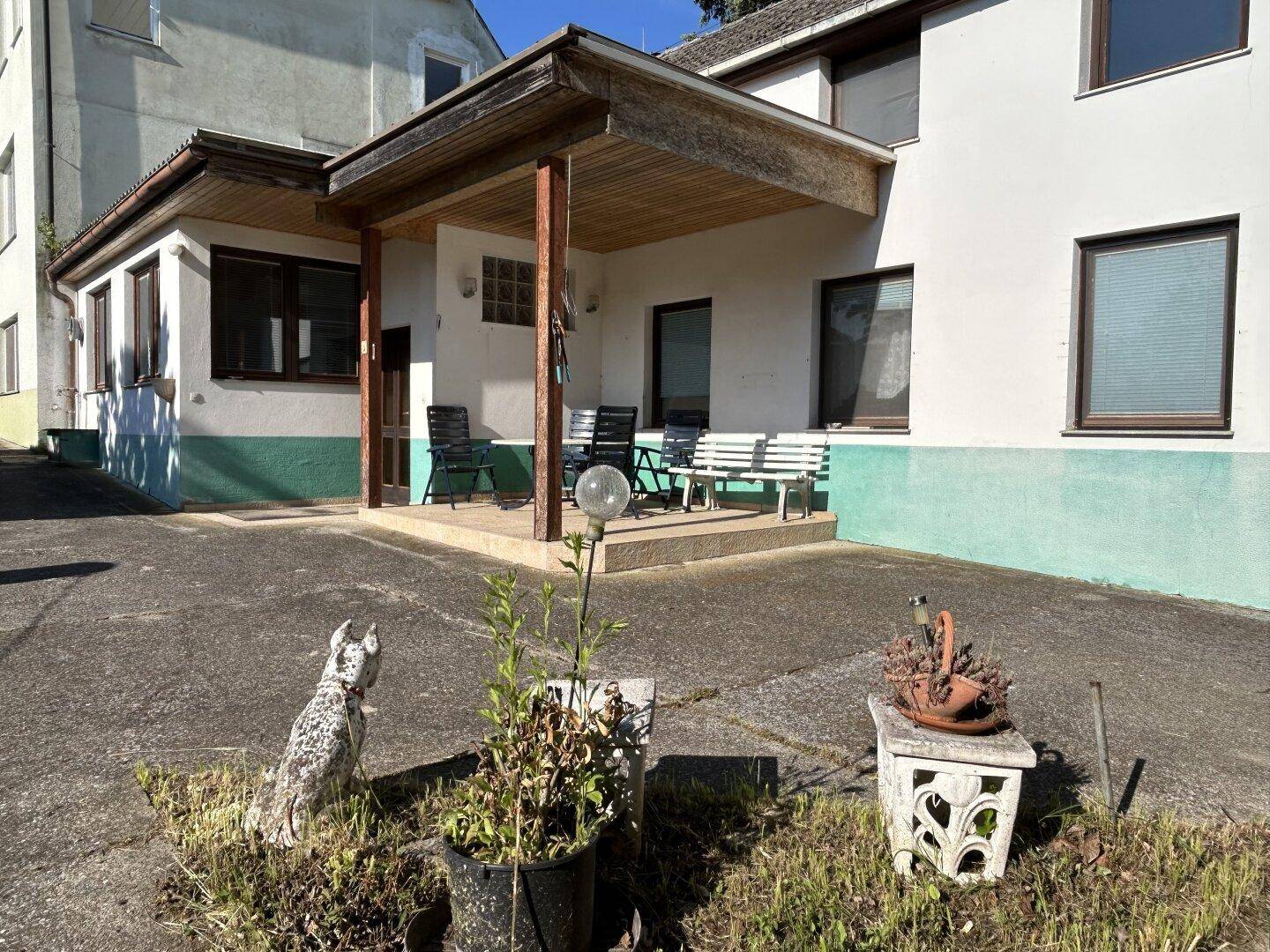 Überdachte Terrasse am Haus mit Sitzgelegenheiten und Blick auf den Garten.