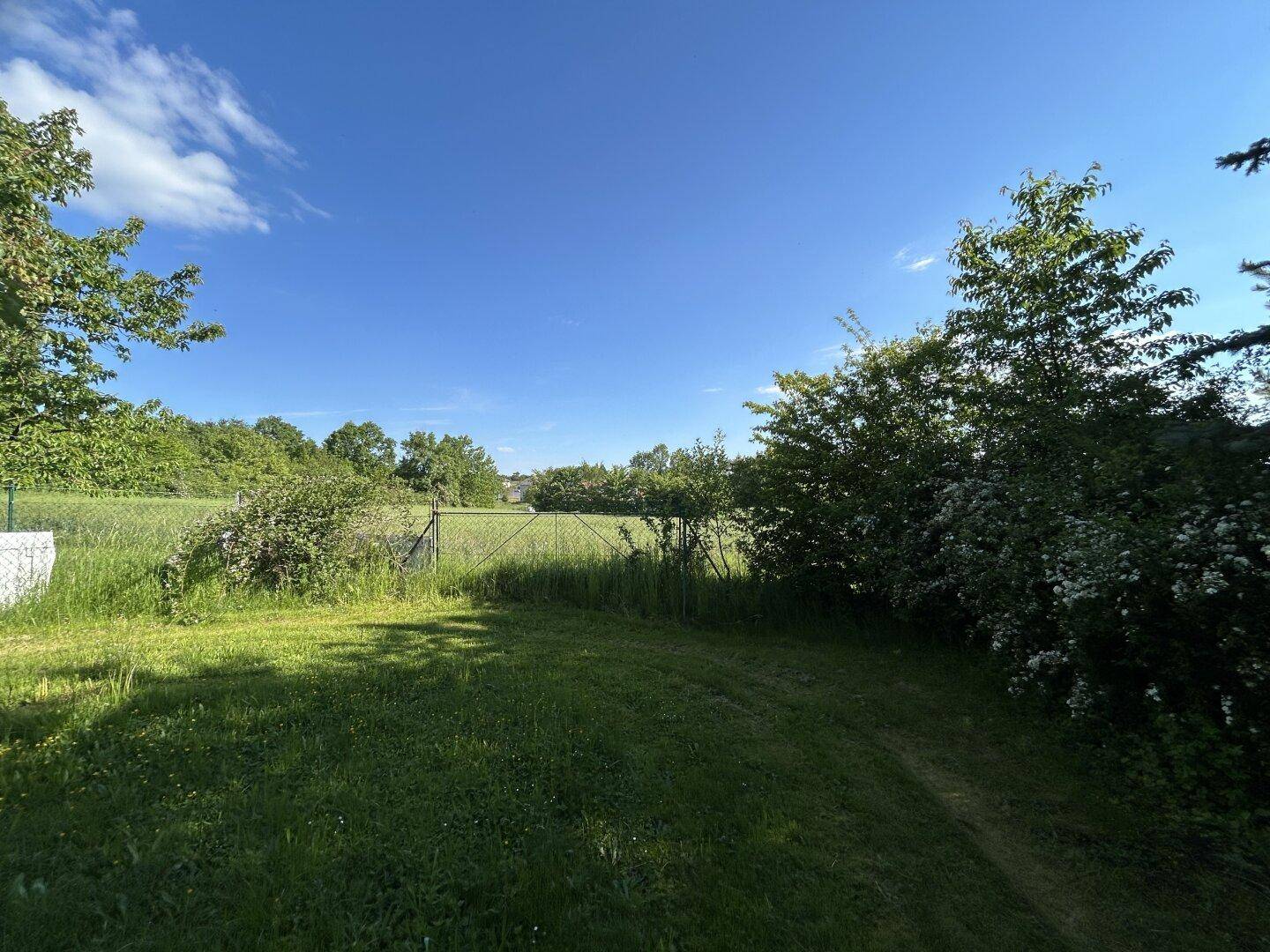 Weitläufiger Gartenbereich mit Blick auf die umliegende grüne Landschaft und Felder.