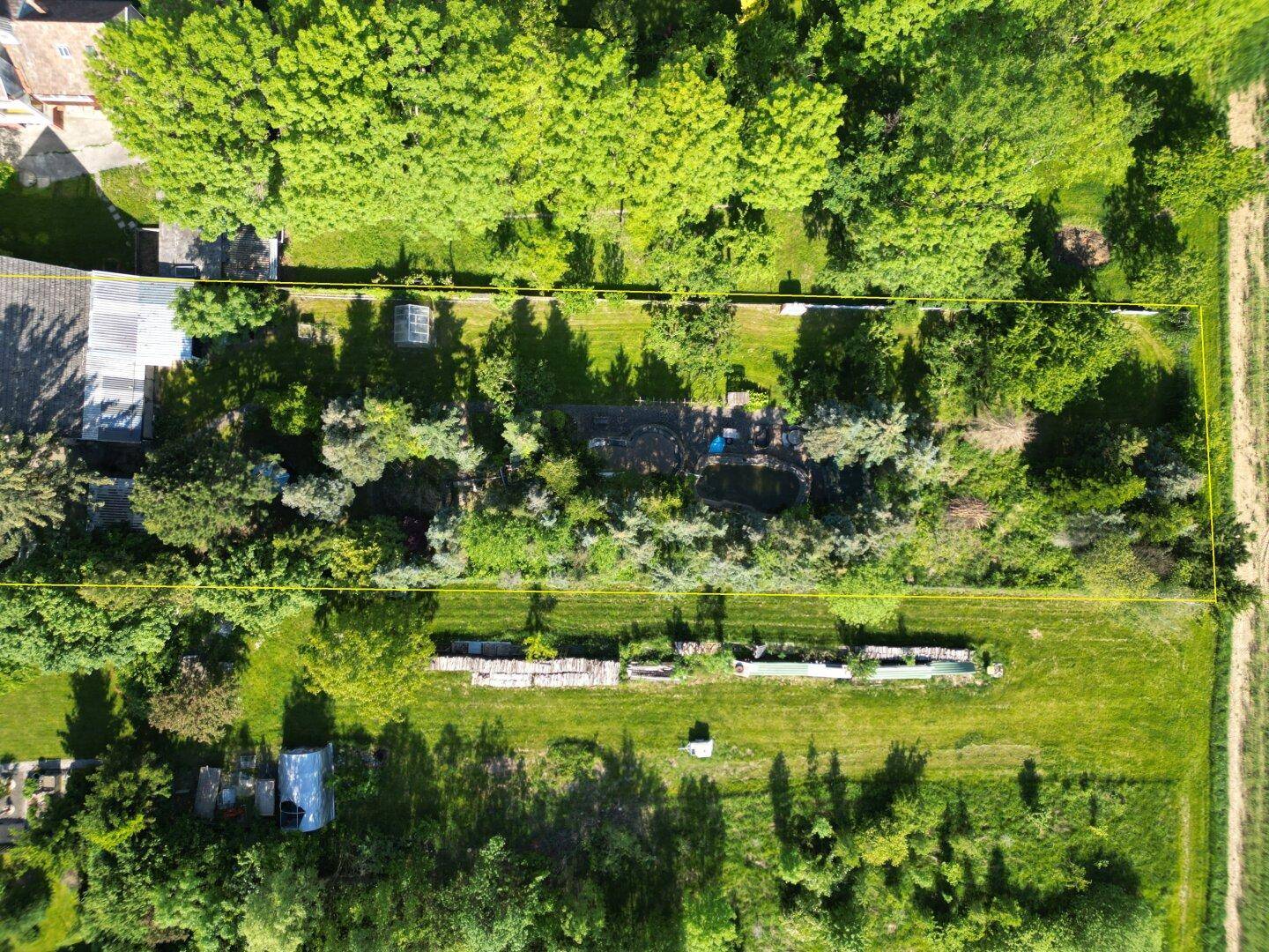 Weitläufiges Grundstück mit Gartenbereichen, Bäumen und angrenzenden Feldern aus der Vogelperspektive.