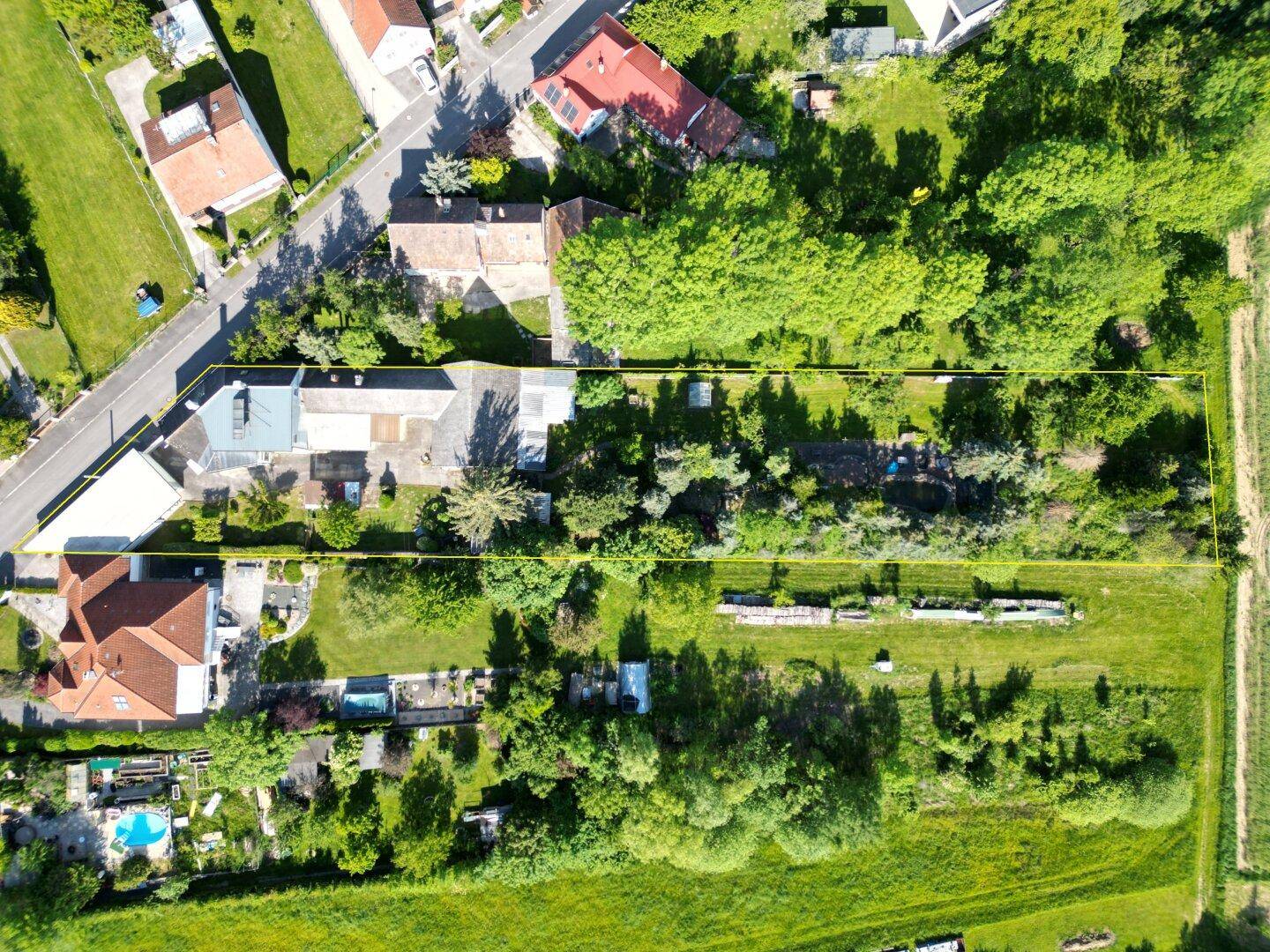 Übersichtliche Luftaufnahme des gesamten Anwesens mit Wohnhaus, Garten und weitläufigem Grundstück.