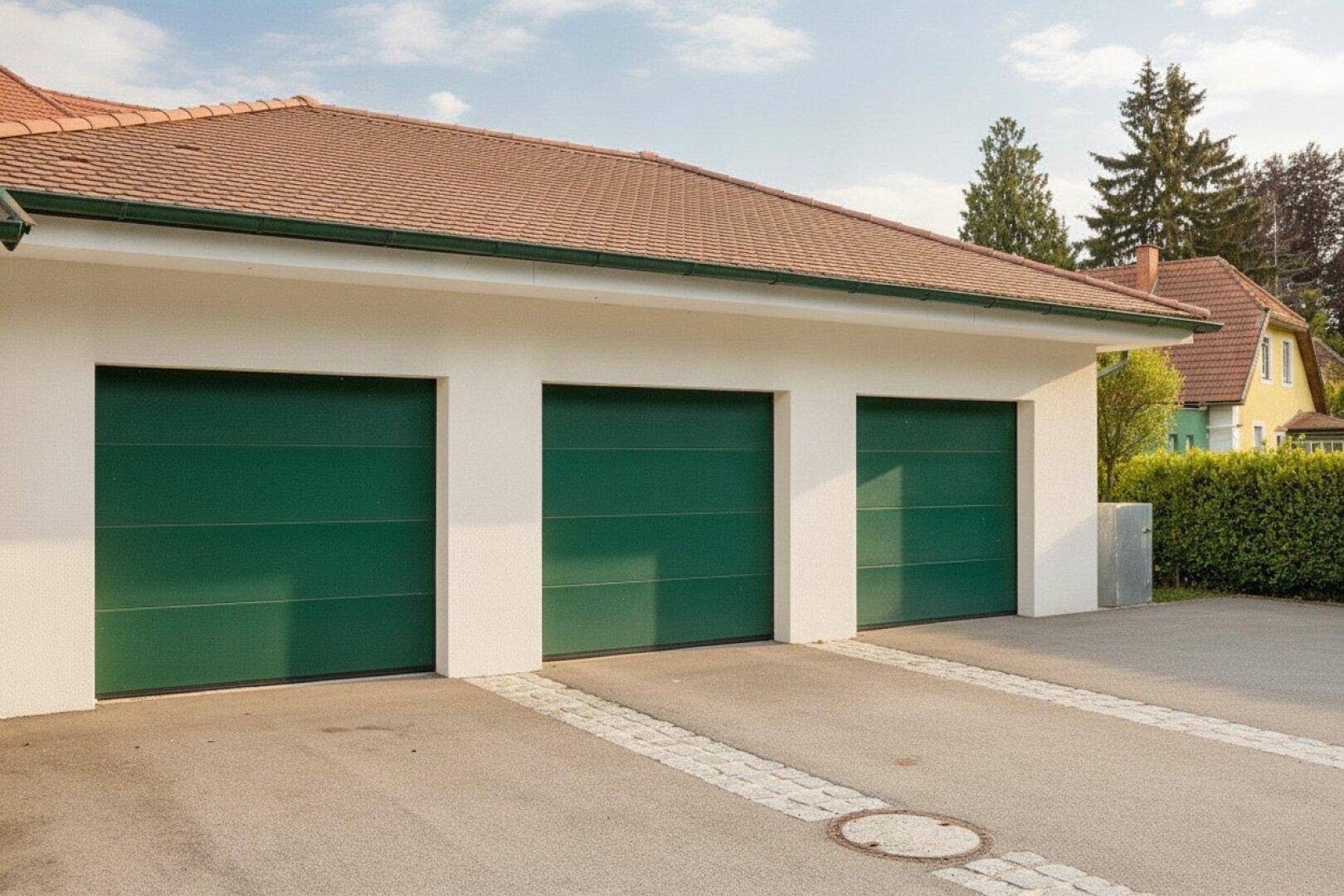 Dreifachgarage mit grünen Toren und gepflasterter Zufahrt.