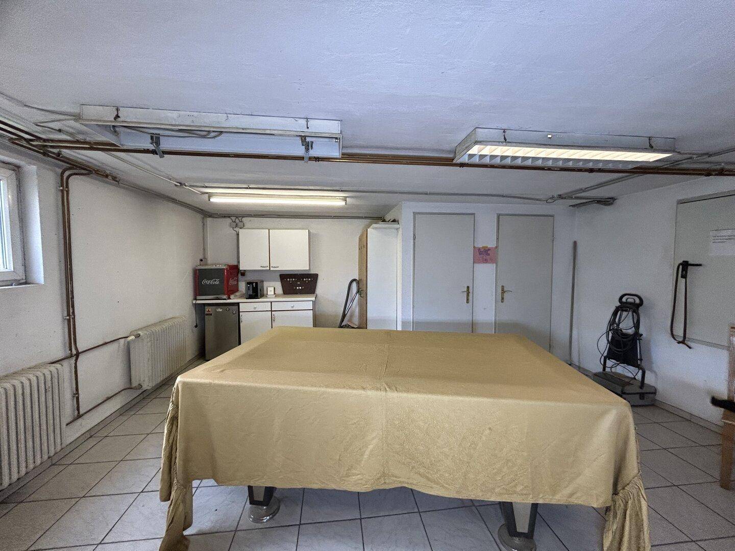 Freizeitraum im Untergeschoss mit Fliesenboden, kleiner Küchenzeile und Billardtisch.
