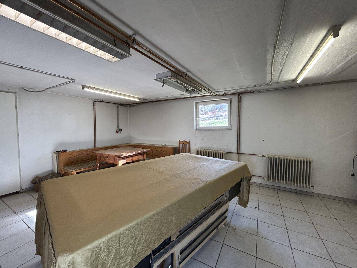Geräumiger Freizeitraum im Untergeschoss mit Fliesenboden, Sitzgelegenheiten und Billardtisch.